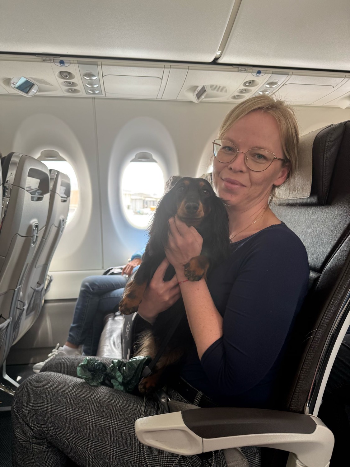 Jirina sitting on an aircraft with Aja held calmly in her arms, cabin windows behind them